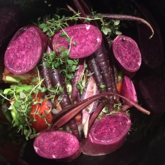 A bowl of salad with purple carrots and beets